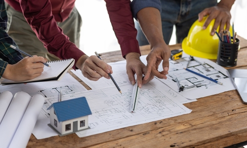 A table with blueprints and hardhats